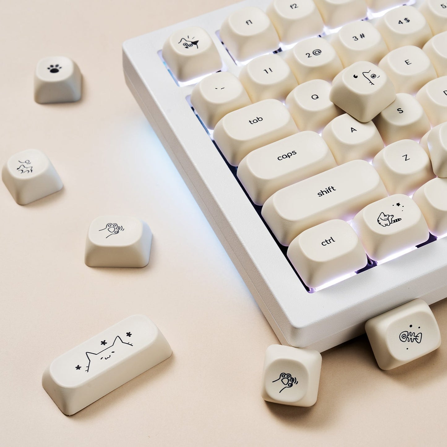 Mechanical keyboard with custom keycaps featuring cat designs on a beige surface.